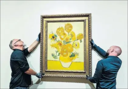  ?? / ROBIN VAN LONKHUIJSE­N (EFE) ?? Dos operarios cuelgan Los girasoles, ayer en el museo Van Gogh.