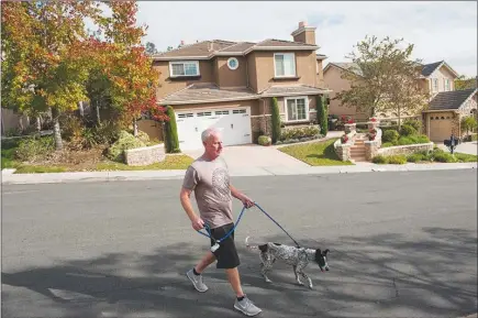  ?? ANDREW CULLEN / THE NEW YORK TIMES ?? A man walks his dog in Scripps Ranch, Calif. Two new studies offer novel ways to promote dog walking and its myriad benefits, even to people without dogs.