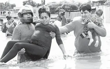  ?? DELMER MARTINEZ/AP ?? Weakened Eta drenches Honduras: A pregnant woman is carried out of a flooded area Thursday in Planeta, Honduras, as the rain-heavy remains of Hurricane Eta flooded homes across Central America. The death toll rose to at least 19. The storm was expected to regather form and head toward Cuba and possibly the Gulf of Mexico by early next week.