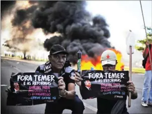  ?? ANDRESSA ANHOLETE/AFP ?? Demonstrat­ors hold banners against Brazilian President Michel Temer during a protest in Brasilia on Wednesday.