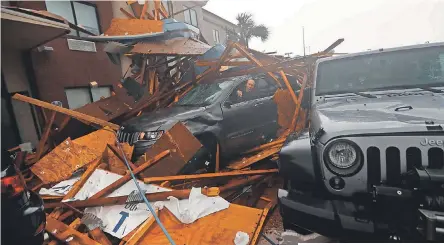  ?? GERALD HERBERT/AP ?? A storm chaser retrieves equipment from his car during the eye of the storm Wednesday after a hotel canopy fell in Panama City Beach, Fla.