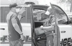  ?? AMY BETH BENNETT/SOUTH FLORIDA SUN SENTINEL ?? Miramar Police officer Rodney Washington advises Daniel Liriano about applying for the Paycheck Protection Program since he is still unable to operate his business, Lion Style Barbershop & Salon in Miramar, during the pandemic.