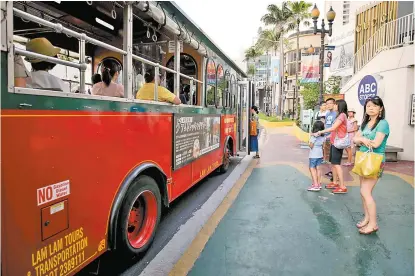  ??  ?? Varias personas esperan para subirse a un autobús en la ciudad de Tamuning, en la Isla de Guam.