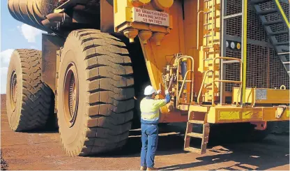  ?? /Reuters ?? Increasing competitio­n: A worker checks a truck loaded with iron ore at Fortescue Metals’ Christmas Creek iron ore mine in the Pilbara region of Western Australia. The region is the world’s largest ironore mining hub.