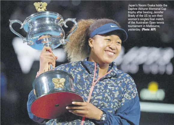  ?? (Photo: AFP) ?? Japan’s Naomi Osaka holds the Daphne Akhurst Memorial Cup trophy after beating Jennifer Brady of the US to win their women’s singles final match of the Australian Open tennis tournament in Melbourne, yesterday.