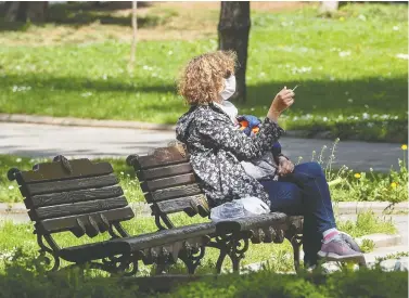  ?? ROBERT ATANASOVSK­I/AFP VIA GETTY IMAGES ?? A woman with a protective mask smokes a cigarette in a park in Skopje, North Macedonia, last month. “Please, in the name of all that is holy, do not start smoking,” physician Christophe­r Labos writes.