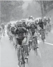  ?? CHRISTOPHE ENA/ THE ASSOCIATED PRESS ?? Michael Rogers of Australia leads the pack in a downpour during the 19th stage of the Tour de France on Friday.