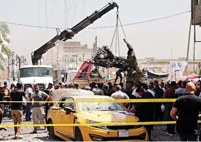  ??  ?? Iraqi security forces remove destroyed vehicles at the site of a deadly bomb attack in Baghdad. (AP)