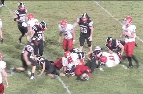  ?? Times photograph by Annette Beard ?? Blackhawk Charlie Holliday, No. 55, is on the bottom of the pile. The Blackhawks beat Green Forest 37/0 Friday night after game delays from torrential rains and lightning.