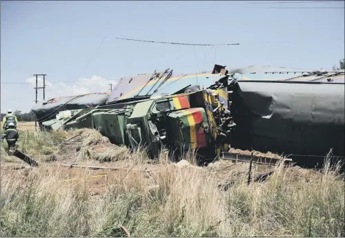  ?? PICTURE: ?? WRECKAGE: Emergency workers and ruined carriages at the scene of a rail accident near Kroonstad, South Africa, in which at least 18 people died.