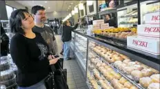  ?? Larry Roberts/Post-Gazette ?? Jennifer and Jason Jeung of Monroevill­e wait to buy a dozen paczki at Oakmont Bakery.