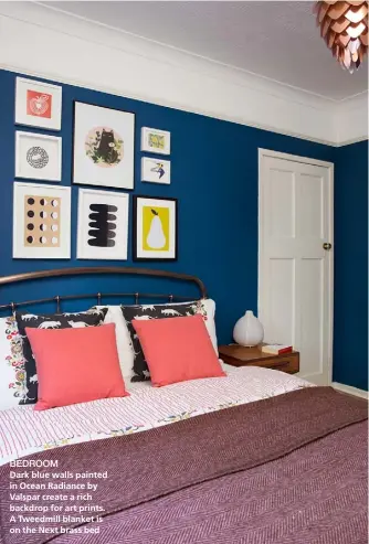  ??  ?? BEDROOM Dark blue walls painted in Ocean Radiance by Valspar create a rich backdrop for art prints. A Tweedmill blanket is on the Next brass bed