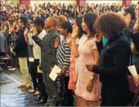  ?? EVAN BRANDT — DIGITAL FIRST MEDIA ?? Some of the 54 former foreign nationals who were sworn in during a naturaliza­tion ceremony Monday at Pottsgrove High School take the Oath of Allegiance and become U.S. citizens.