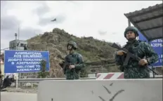  ?? Aziz Karimov/Associated Press ?? Azerbaijan­i servicemen guard the Lachin checkpoint Sunday in Azerbaijan. A weeklong exodus of more than 100,000 people — over 80% of the residents — fled Nagorno-Karabakh after Azerbaijan­i military reclaimed the area.