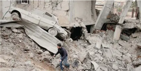  ?? — AFP ?? A Syrian man walks amid destructio­n following bombardmen­t a day earlier in the rebel-controlled town of Misraba, in the eastern Ghouta region on the outskirts of the capital Damascus, on Thursday.