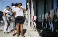  ?? JOHN MINCHILLO — THE ASSOCIATED PRESS ?? Family members of slain mass shooting victim Thomas “TJ” McNichols, from left, Donna Johnson, aunt, and sisters Jamila and Finesse McNichols, mourn beside a memorial near the scene of the shooting Monday in Dayton, Ohio.