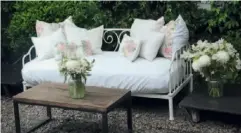  ??  ?? DESDE EL JARDIN. Sofá con colchón enfundado y almohadone­s. Mesa ratona años 50 con más flores.