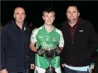  ??  ?? Brian Cushe, Naomh Eanna captain, accepting the Michael Shortle Memorial Cup from John Shortle representi­ng the Shortle family, and Dean Goodison of People Newspapers (sponsors).