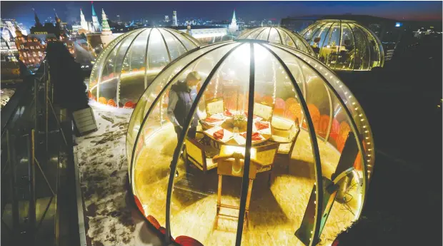  ?? MAXIM SHEMETOV / reuters ?? A waiter sets a table inside a dining pod with a view of the Kremlin and Red Square on the rooftop of the Ritz-carlton hotel in Moscow, Russia.