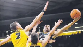  ?? Charlie Neibergall / ?? Michigan State guard Miles Bridges (right) drives to the basket as Iowa's Jack Nunge (2) and Luka Garza defend during the second half in Iowa City, Iowa. Bridges scored 25 points as Michigan State won.