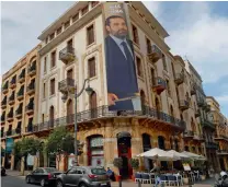  ??  ?? A poster showing Lebanese Prime Minister Saad Hariri with Arabic that reads,
“We are all with you," hangs from a building, in downtown Beirut on Tuesday. Hariri has said he will return home in the coming days —