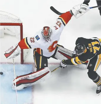  ?? - Associated Press: Gene J. Puskar ?? Evgeni Malkin, des Penguins de Pittsburgh, surprend le gardien des Flames de Calgary, Jon Gillies.