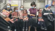  ?? MARY ALTAFFER - STAFF, AP ?? A family, some wearing face masks and some not, ride the subway Monday in the Brooklyn borough of New York.