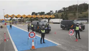  ?? (Nacho Doce/Reuters) ?? POLICE OFFICERS wait to check vehicles yesterday at the last toll gate entering Spain from France in La Jonquera, Spain.