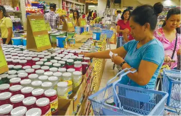  ?? SUNSTAR FOTO / ARNI ACLAO ?? CHECKING IT TWICE. A woman checks her grocery list while shopping in a supermarke­t in downtown Cebu City.