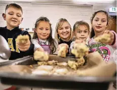  ?? FOTO: RALPH MATZERATH ?? Nico, Fatma, Sarah und Lilly (v. l.) mit dem Teig, den sie gemeinsam angerührt haben. Svenja Holtschnei­der (m.) hat ihnen gezeigt, wie’s geht.