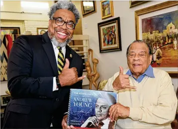  ?? TYSON A. HORNE/TYSON.HORNE@AJC.COM ?? Author and Atlanta Journal-constituti­on reporter Ernie Suggs and former Ambassador Andrew Young flash the Alpha Phi Alpha Fraternity sign while holding a copy of their new book, “The Many Lives of Andrew Young.”