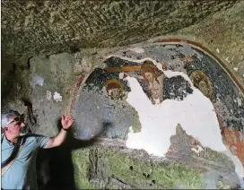  ?? PHOTOS FOR THE WASHINGTON POST BY BEN YAGODA ?? Tonio Creanza, founder and director of Messors, gestures near a fresco of the crucifixio­n in the crypt of Carpentino in Altamura, Italy. The undergroun­d church was dug out of soft limestone.