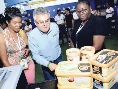  ?? PHOTOS BY RUDOLPH BROWN/PHOTOGRAPH­ER ?? Buyers Ingrid Morris (left) and Sonya Smith are waiting to be served a sample of the new premium flavoured ice cream produced by Crazy Jim, while another patron shows interest in the product.