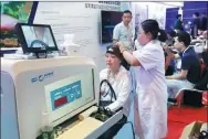  ?? WANG ZHUANGFEI / CHINA DAILY ?? A visitor tries out a specialist machine which performs a medical checkup at the ongoing fair.