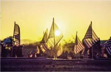  ?? MICHAEL CHOW/THE REPUBLIC ?? The sun rises over flags decorating grave markers at the National Memorial Cemetery of Arizona on Sunday.