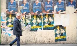  ?? AFP ?? A man walks past vandalised campaign posters of French presidenti­al election candidate in Paris, on Friday