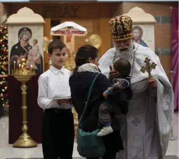  ?? MARTA IWANEK/TORONTO STAR ?? Father Roman Galadza greets parishione­rs at St. Elias the Prophet Ukrainian Catholic Church’s temporary facilities inside St. Augustine Secondary School in Brampton. The congregati­on has been meeting there since an April fire.