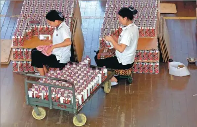  ?? STEPHEN SHAVER / UPI PHOTO VIA NEWSCOM ?? Workers inspect, label and box bottles of Moutai at Kweichow Moutai Company’s distillery in Maotai township, Guizhou province.