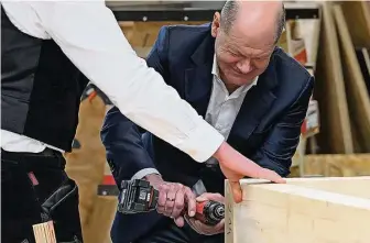  ?? Foto: dpa/R. Michael ?? Wenn ein Bundeskanz­ler und Jurist zum Akkuschrau­ber greift: Olaf Scholz in Aktion beim Holzbau Lepski.