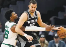  ?? Winslow Townson / Associated Press ?? Boston Celtics guard Marcus Smart (left) reaches in to try to steal the ball from the Sacramento Kings’ Nemanja Bjelica during the second quarter of a game in November 2019.