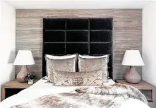  ??  ?? This guest bedroom has a wallpapere­d accent wall, upholstere­d headboard and velvet pillows from Rusty Arena’s Oushak collection for RH (Restoratio­n Hardware).
