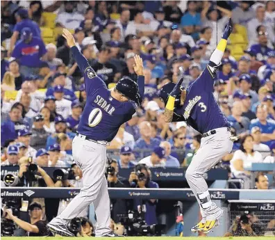  ?? MATT SLOCUM/ASSOCIATED PRESS ?? Milwaukee’s Orlando Arcia (3) celebrates with third base coach Ed Sedar after Arcia hit a home run in Game 3 of the NLCS Monday.