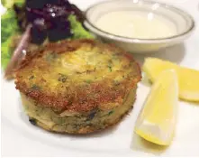  ??  ?? Absolute love: Wolfgang’s crab cake served with tartar sauce, lemon wedges and a side salad