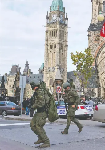  ?? WAYNE CUDDINGTON FILES ?? RCMP tactical officers cross the road heading toward the Langevin Block as police responded to a terrorist attack on Parliament Hill on Oct. 22, 2014.