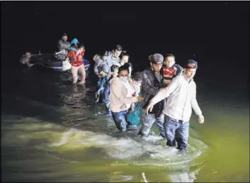  ?? Dario Lopez-Mills The Associated Press ?? Migrant families, mostly from Central American countries, wade through shallow waters Wednesday after being delivered by smugglers on rafts on U.S. soil in Roma, Texas.