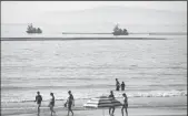  ?? MYUNG J. CHUN/LOS ANGELES TIMES ?? Beachgoers at Newport Beach enjoy the afternoon as boats drag oil booms offshore on Oct. 3, 2021.