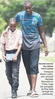  ?? RICARDO MAKYN/ MULTIMEDIA PHOTO EDITOR ?? Tremayne Brown (right), who rescued Renaldo Reynolds on Friday, hugs the youngster as they walk through the community.