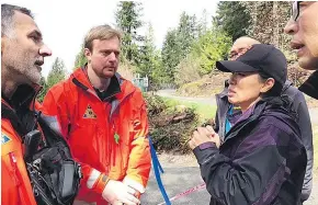  ?? DENISE RYAN ?? Susan Choi speaks to search and rescue workers about her sister, Iris, one of five hikers who fell off Mount Harvey.