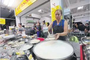  ?? VARUTH HIRUNYATHE­B ?? A self-employed food vendor serves soy milk at a restaurant on Banthat Thong Road.