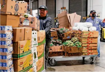  ?? Photos by Jessica Christian/The Chronicle ?? Miguel Sanchez (left) helps haul pallets at Alameda County Food Bank in Oakland. The charity estimates that 1 in 4 Alameda County residents is experienci­ng food insecurity, up from 1 in 5 before the pandemic.